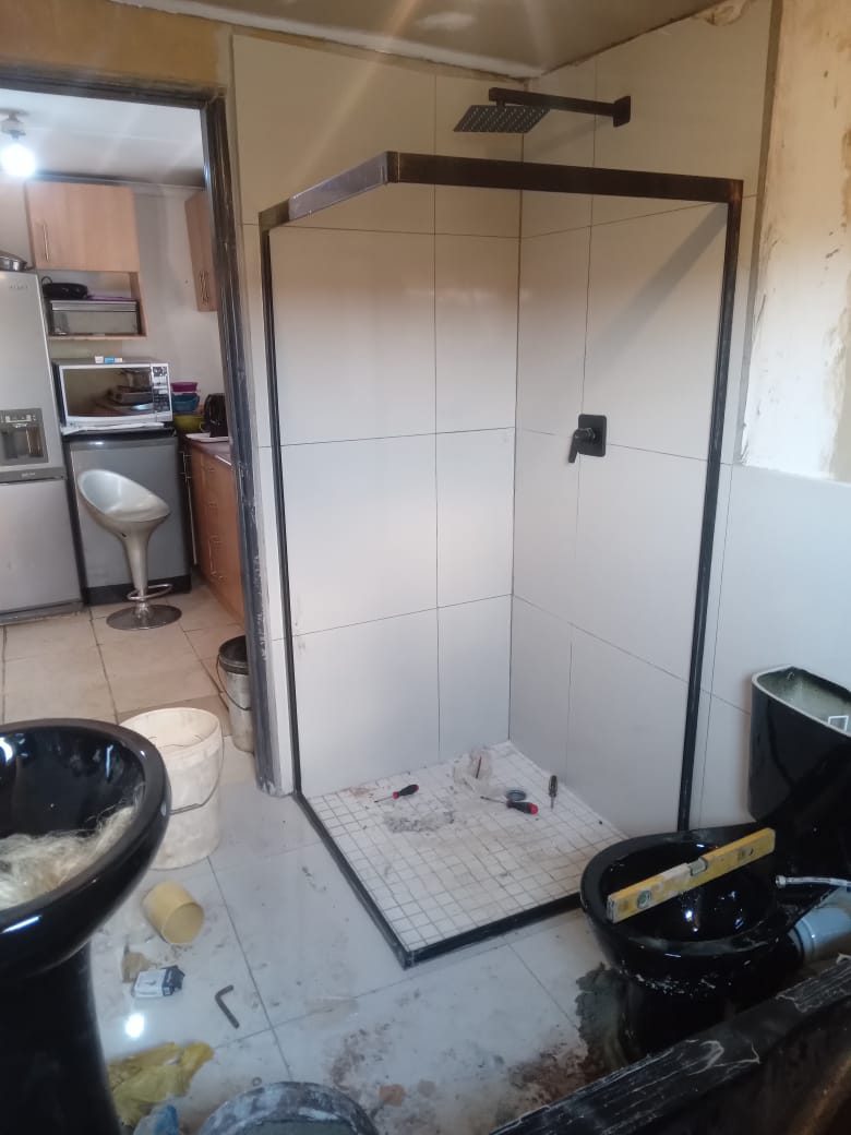 Black-framed walk-in shower enclosure installed in a tiled bathroom